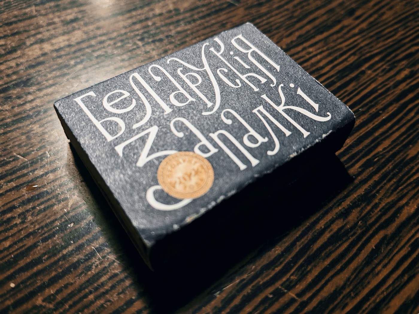 Коробок спичек с декоративным шрифтом на темном фоне.