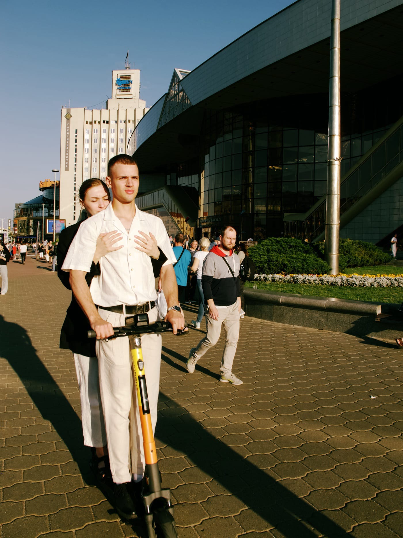 Парень и девушка едут на самокате по летнему городу