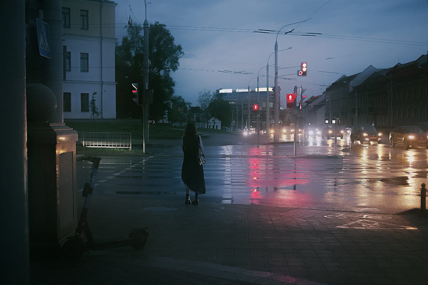 Девушка стоит на пешеходном переходе. Вечерний летний город после дождя.
