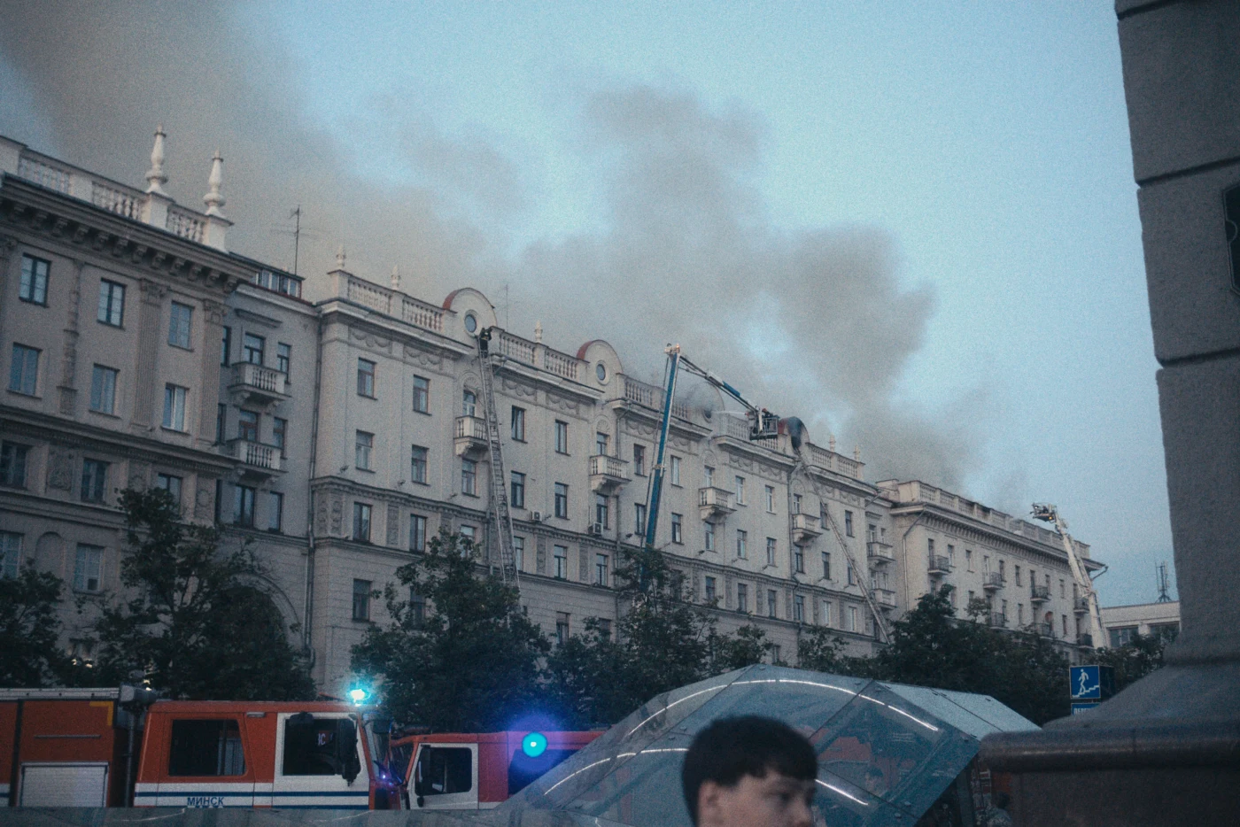 Smoke rising above a building, with fire trucks and equipment at the scene.