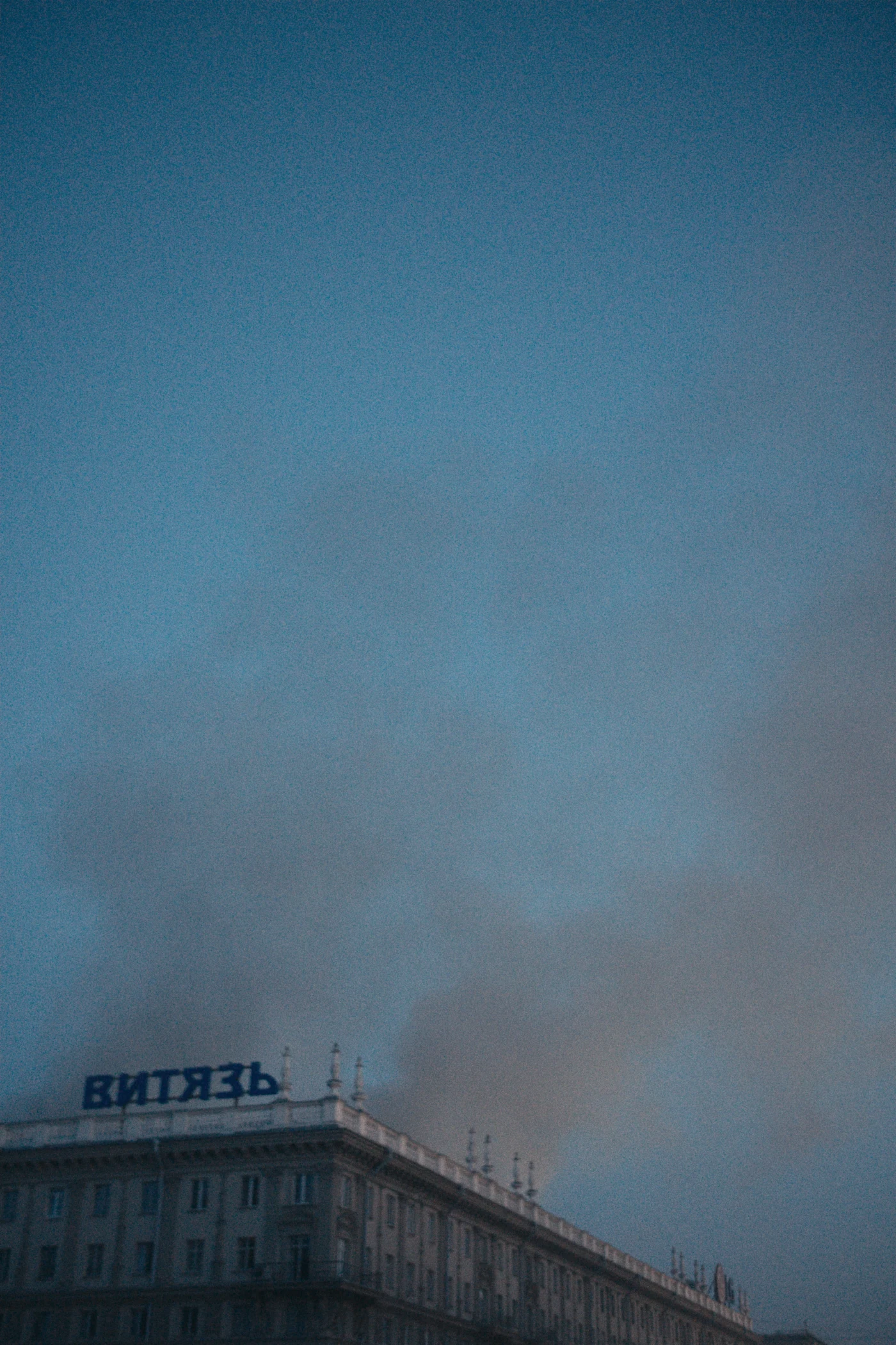 Smoke and a building with the word “ВИТЯЗЬ” are visible against the evening sky.