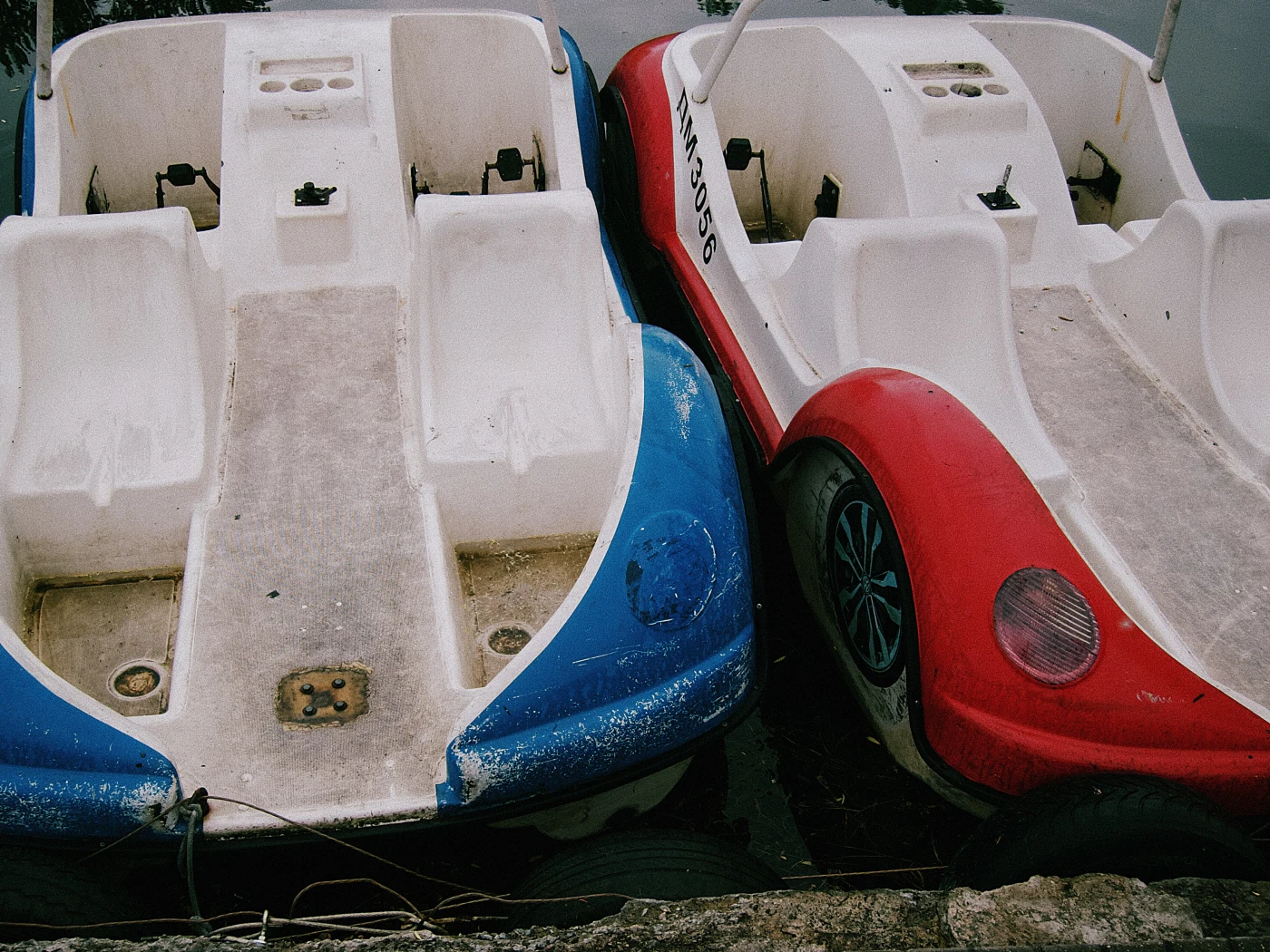 Blue and red water bikes on the shore, next to each other, with visible signs of use.