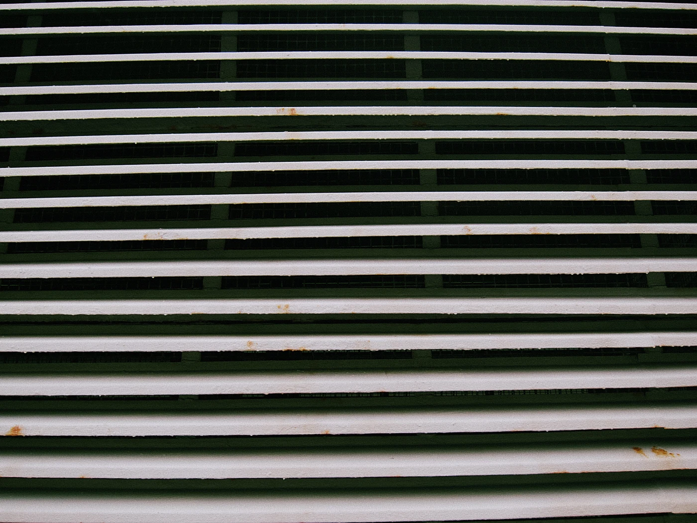 Rusty metal grates with horizontal stripes in green and white.