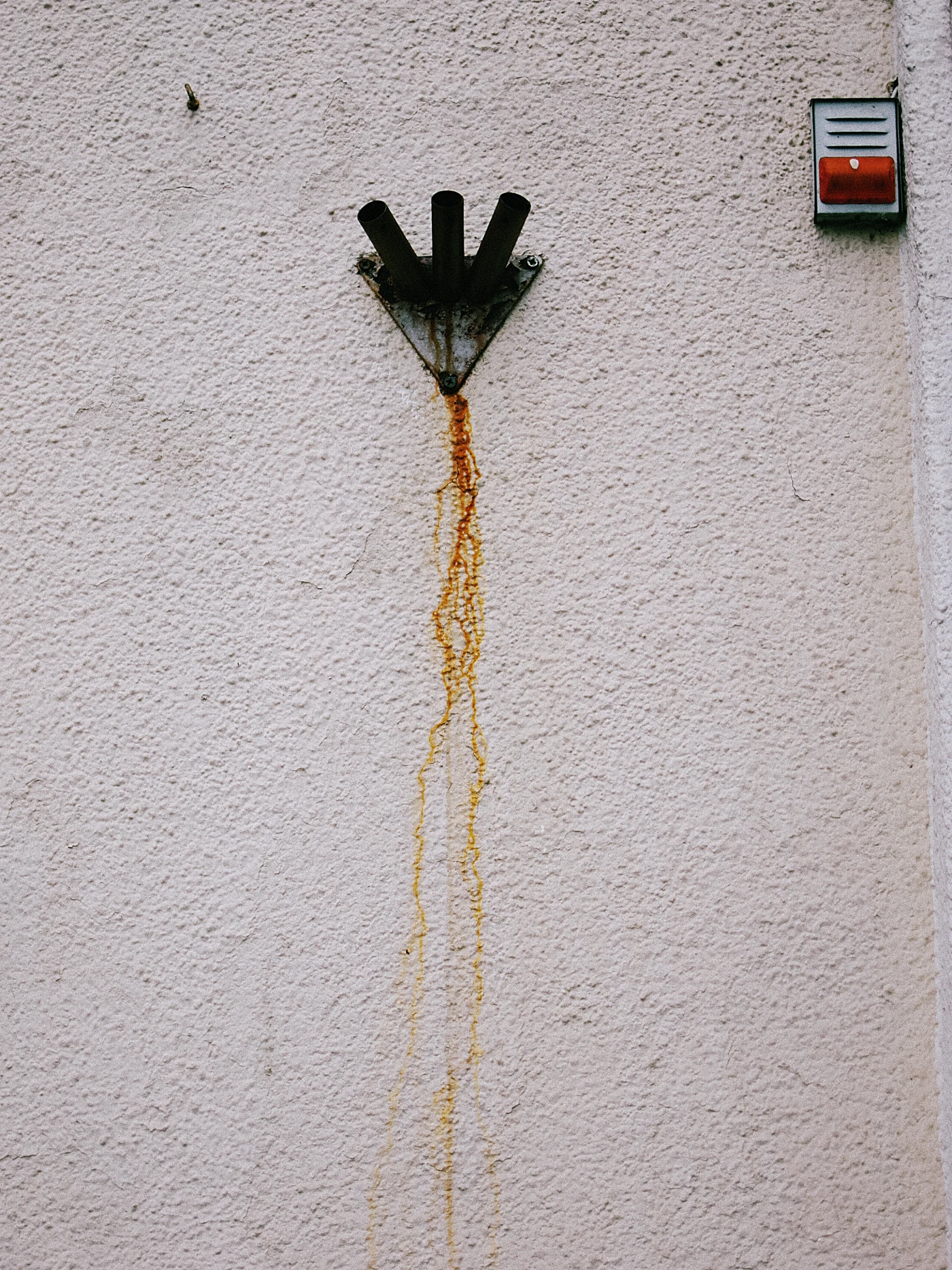 A metal element on the wall releases rusty water, leaving stains on the surface.
