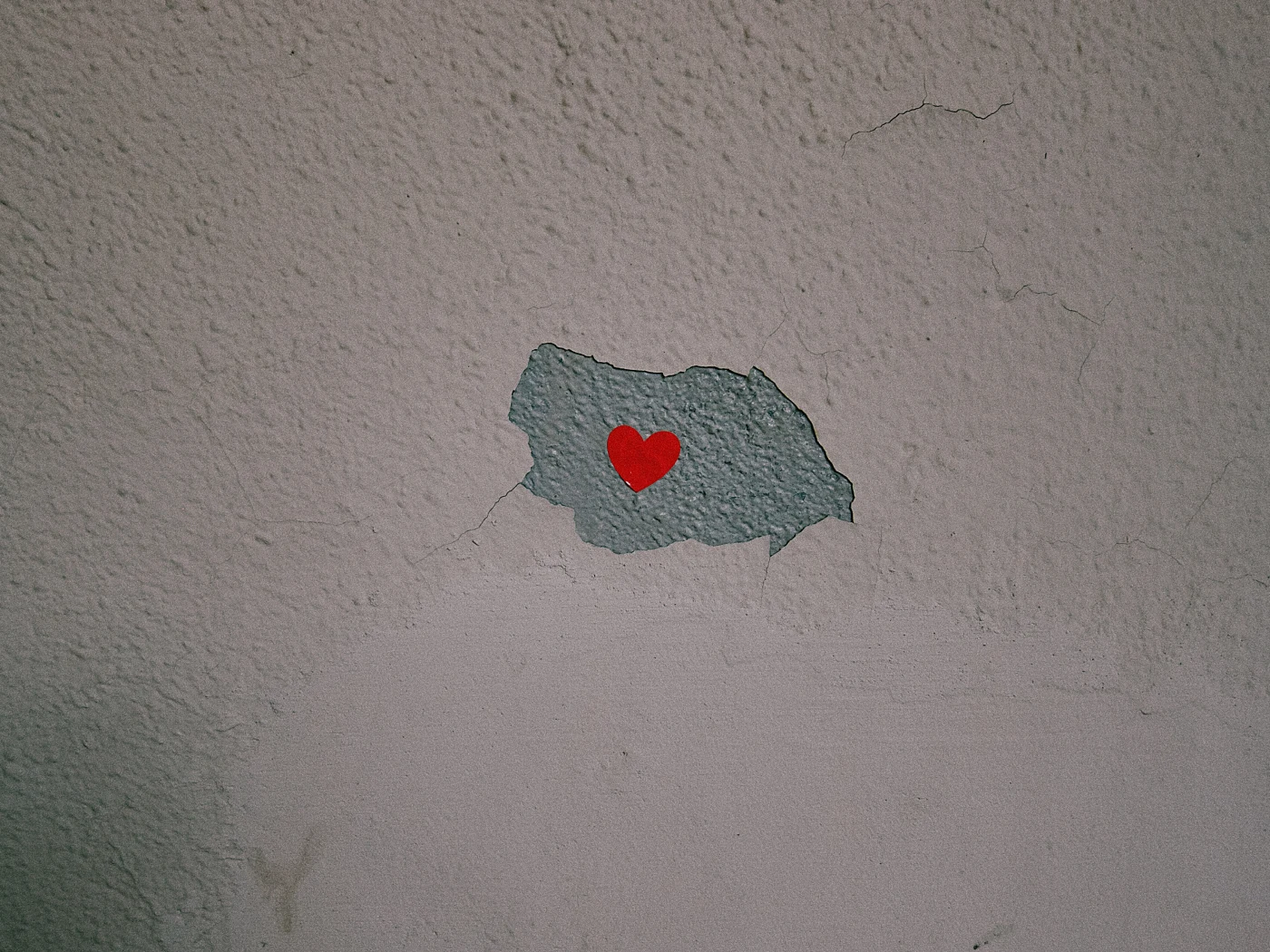 An exposed patch on a wall with a heart painted in red.