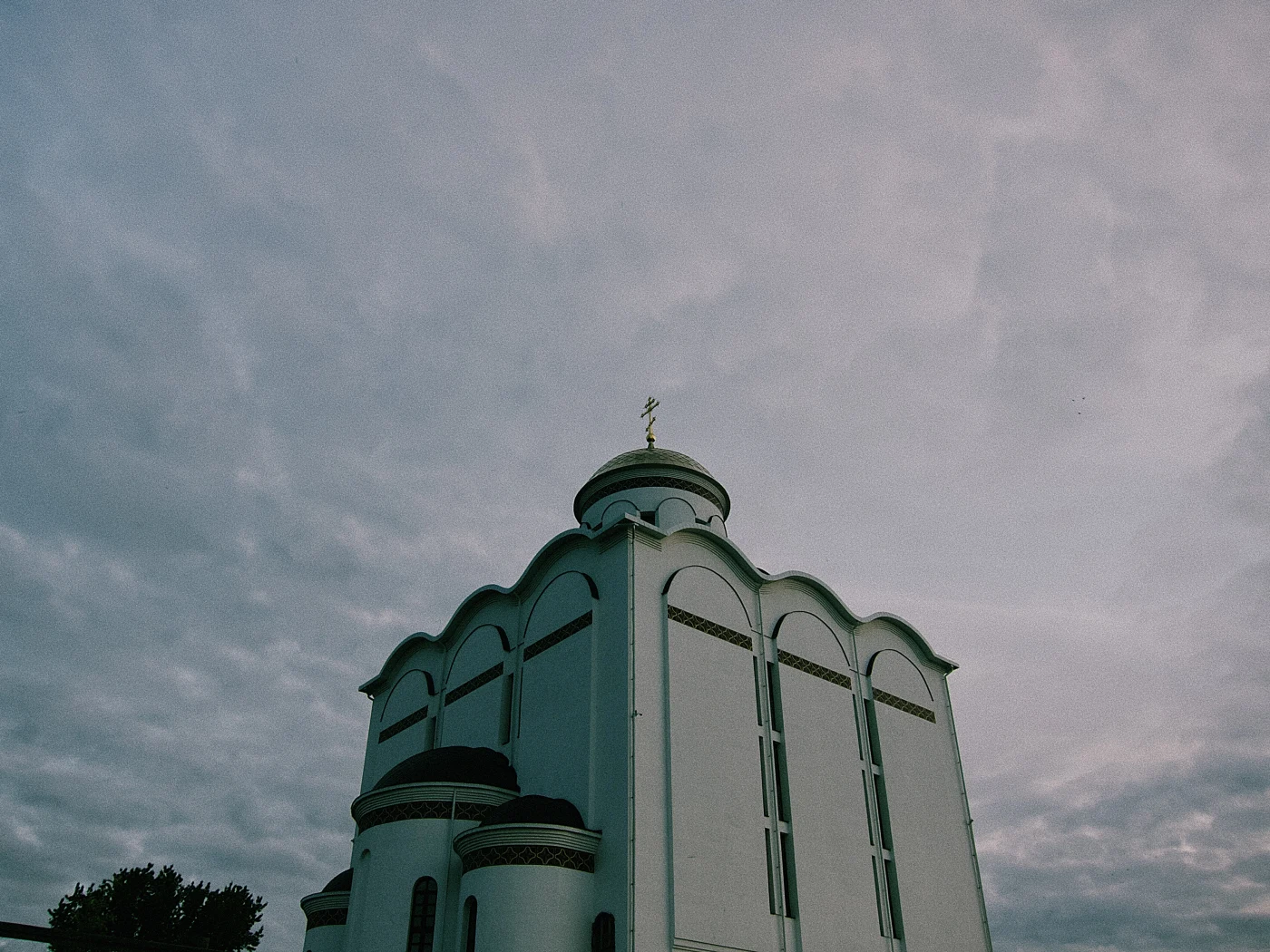 A white church with domes against a cloudy sky.