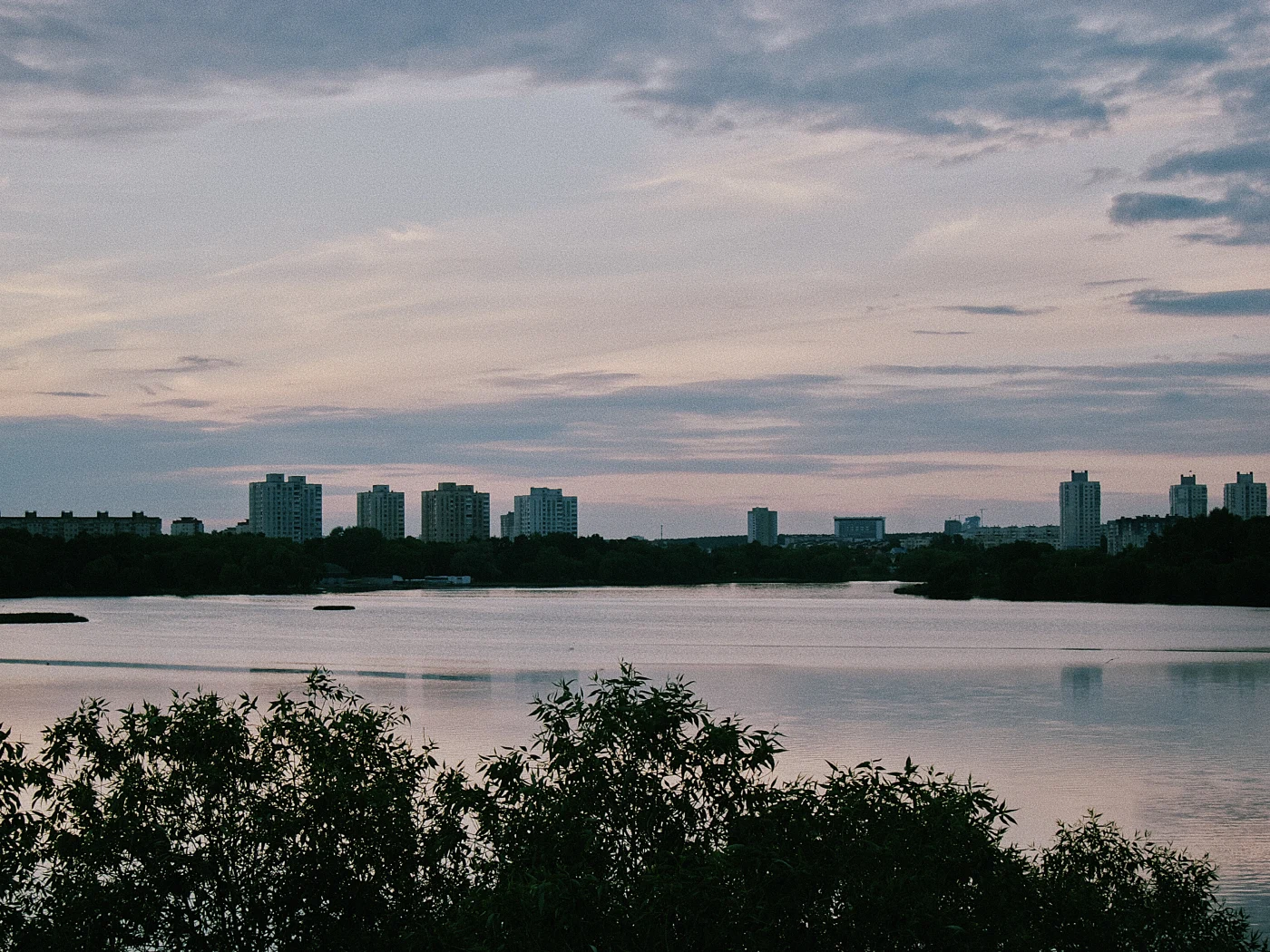 A view of the river and city buildings against an evening sky with clouds.