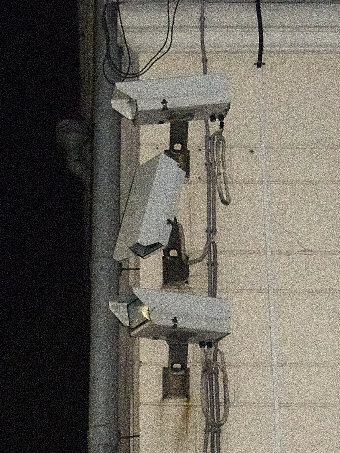 Three security cameras mounted on the wall of a building, with wires and brackets.
