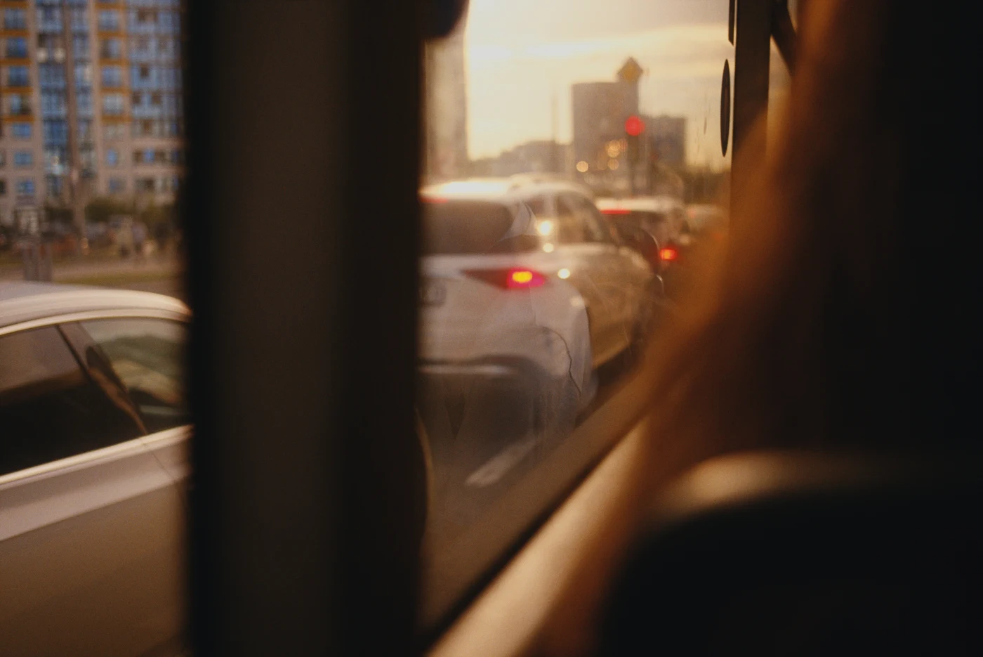 A view from a window of traffic on the road, with evening light and moving cars.
