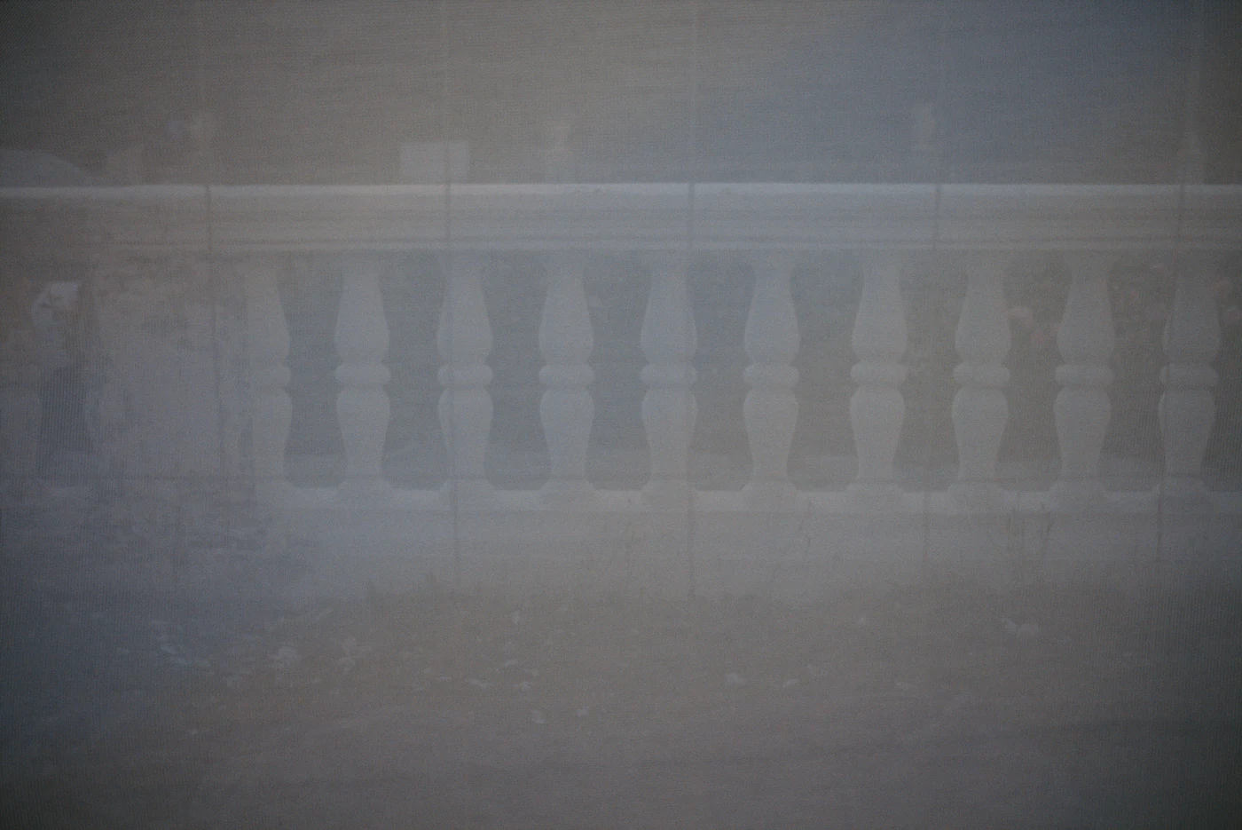 A blurred view of a balustrade with white columns against an indistinct landscape.