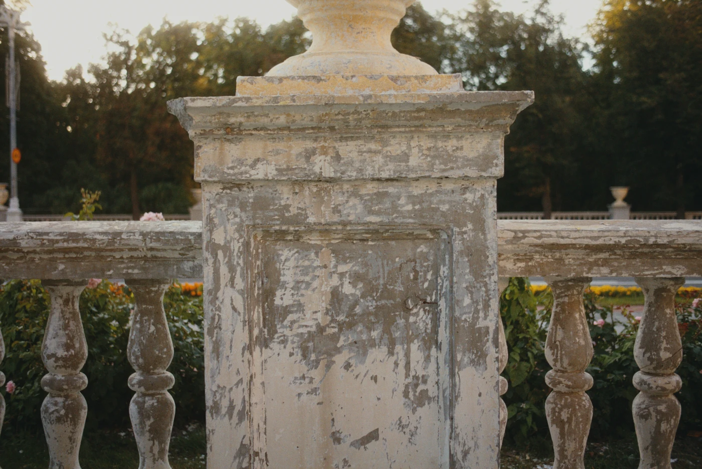 An old balustrade with peeling paint against a green park.
