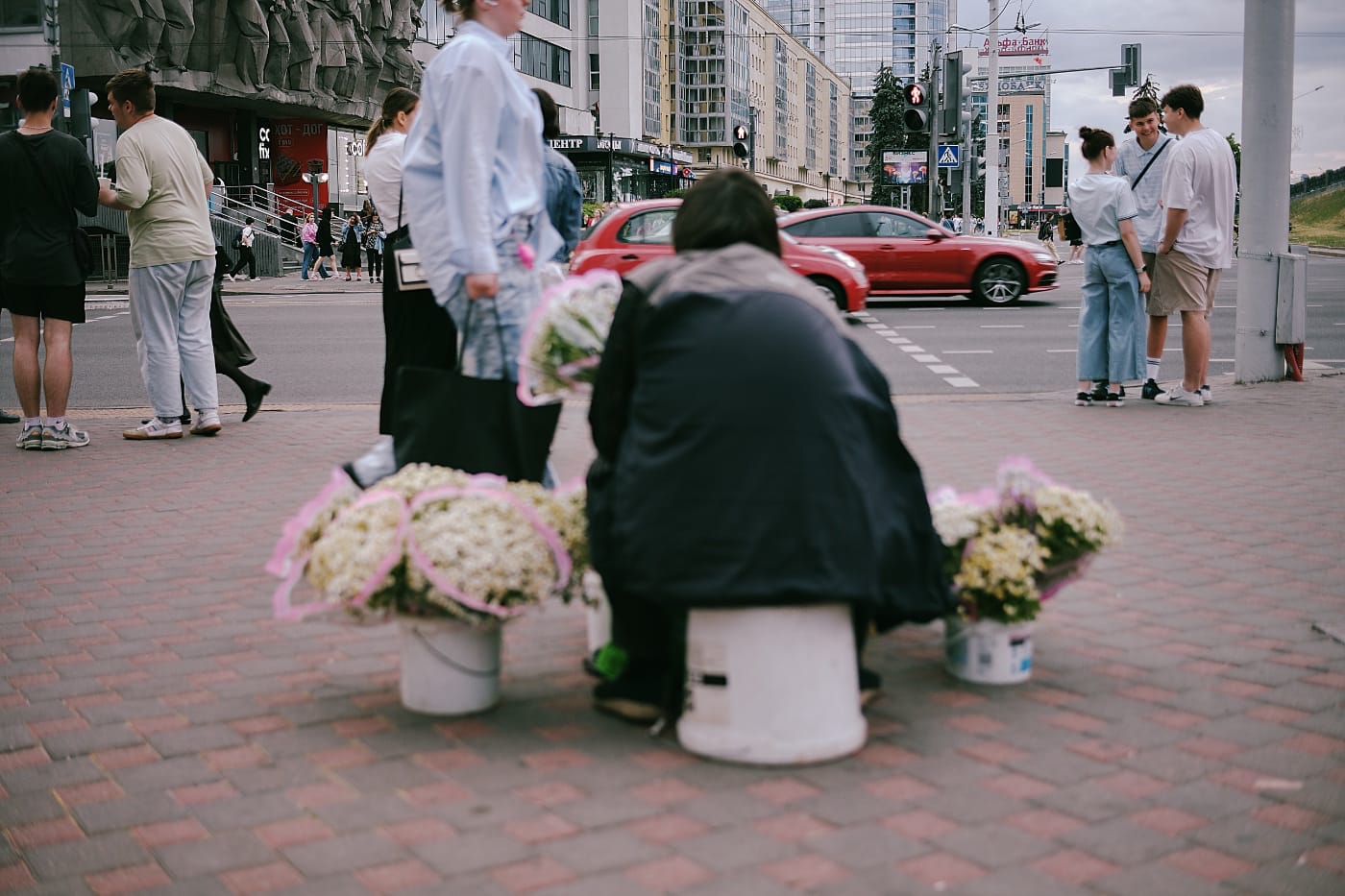 Женщина сидит на ведре и продаёт цветы