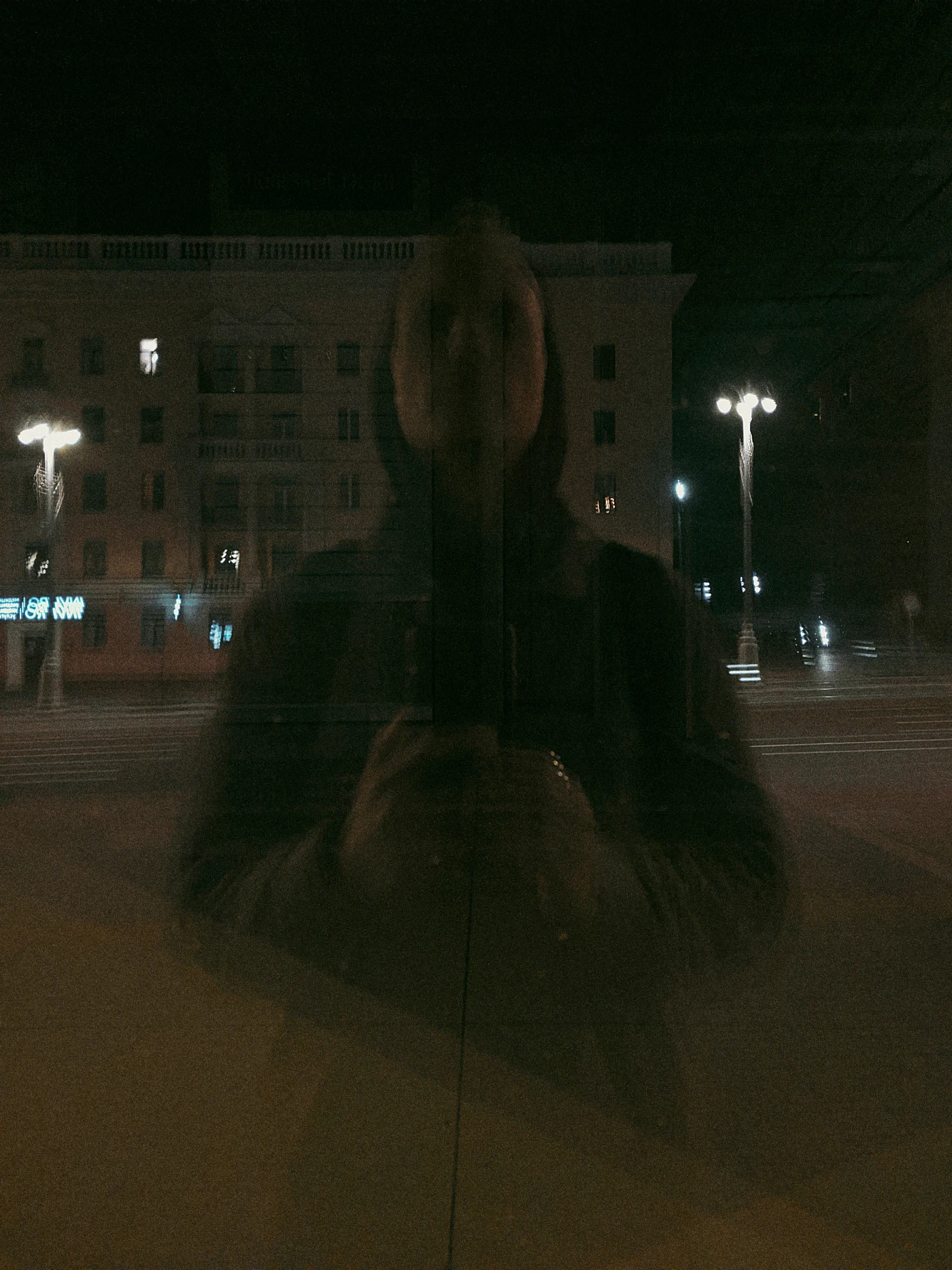 Отражение человека в стекле на фоне ночного города.