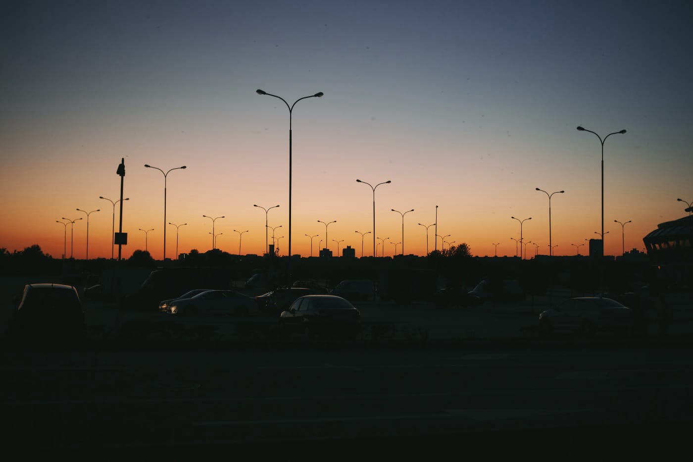 Lamp posts in a parking lot against an orange sunset