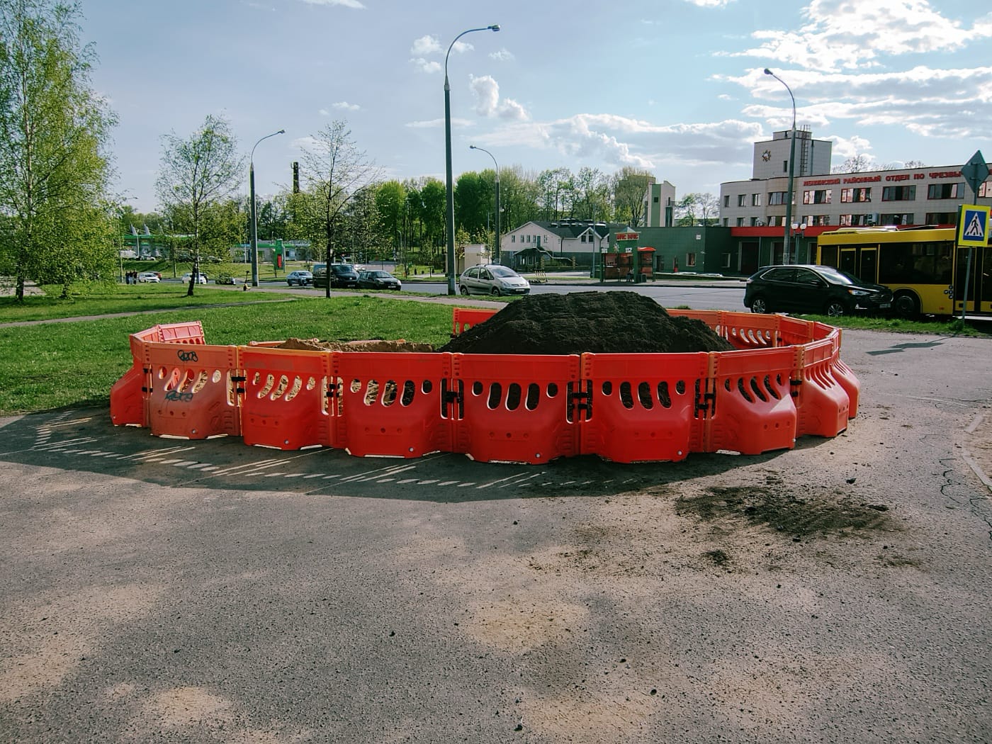 Куча асфальта огорожена красным пластмассовым забором в весеннем городе