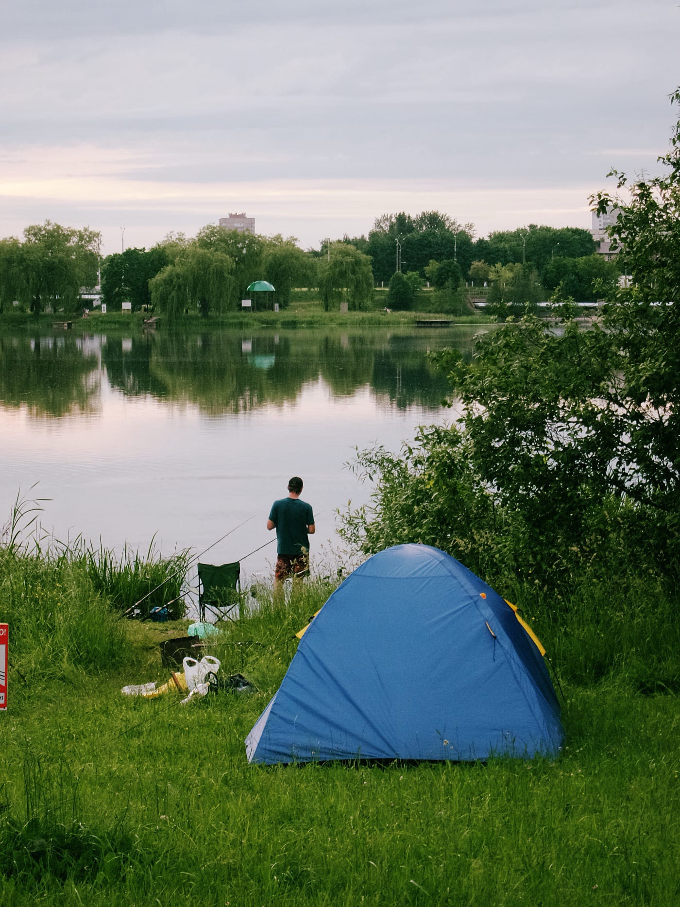 Мужчина стоит возле синей палатки на берегу Чижовского водохранилища в Минске
