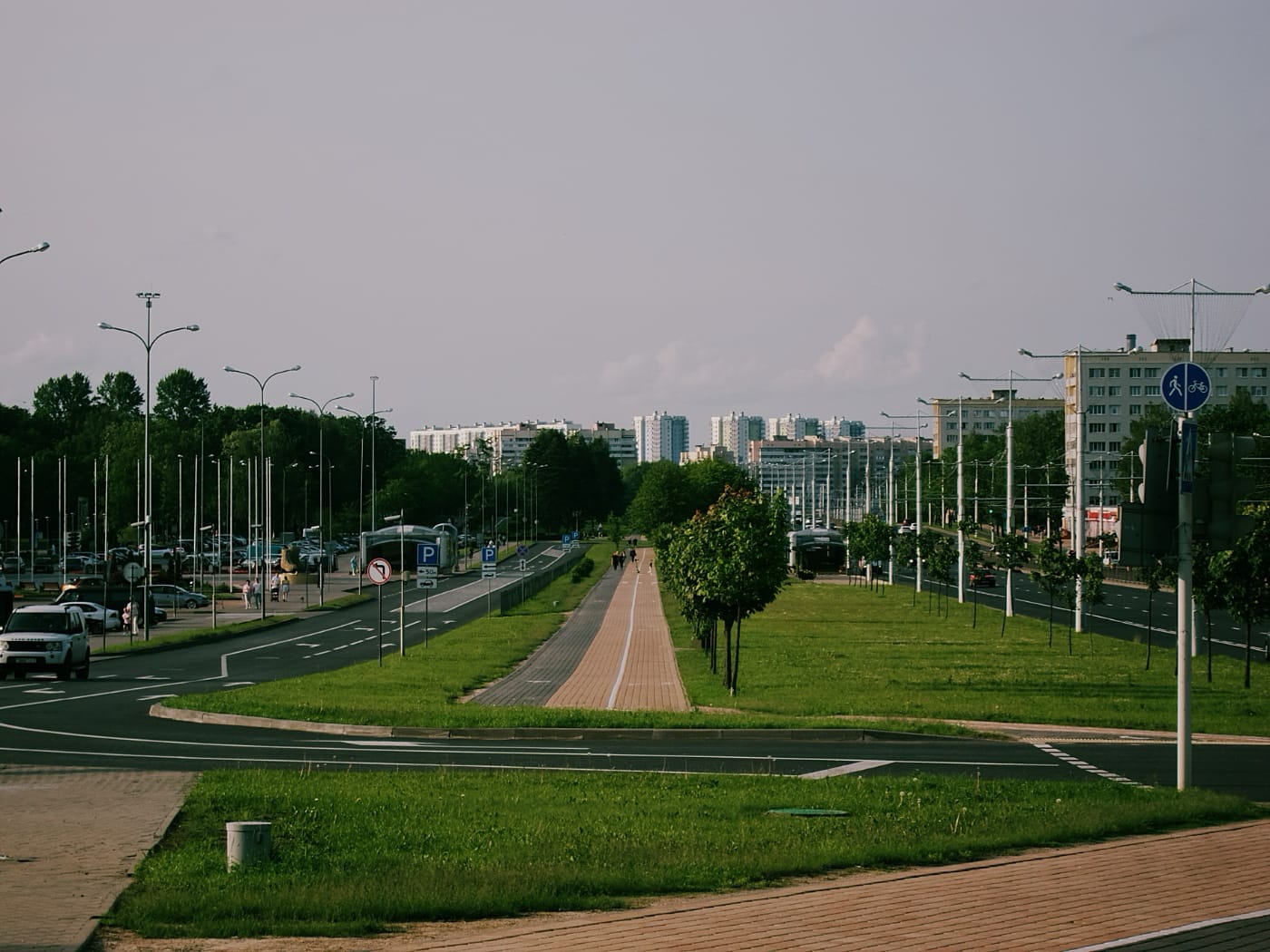 Панорама города: уходящая вдаль велодорожка, дома, дорога.