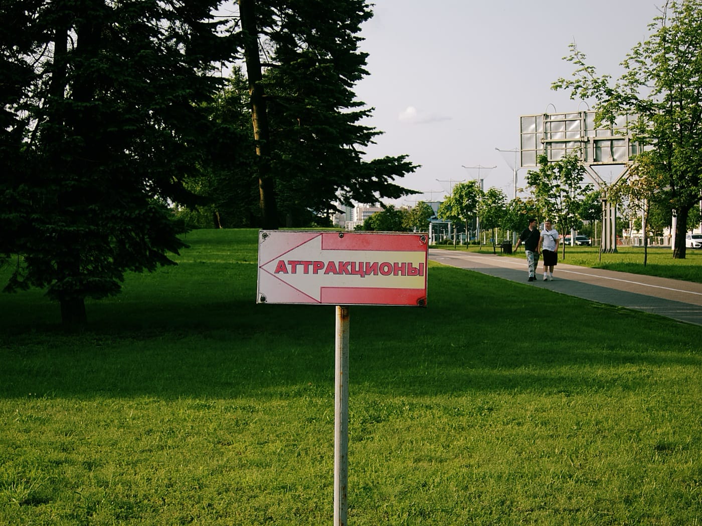 Табличка сострелкой «Аттракционы» в вечернем летнем парке