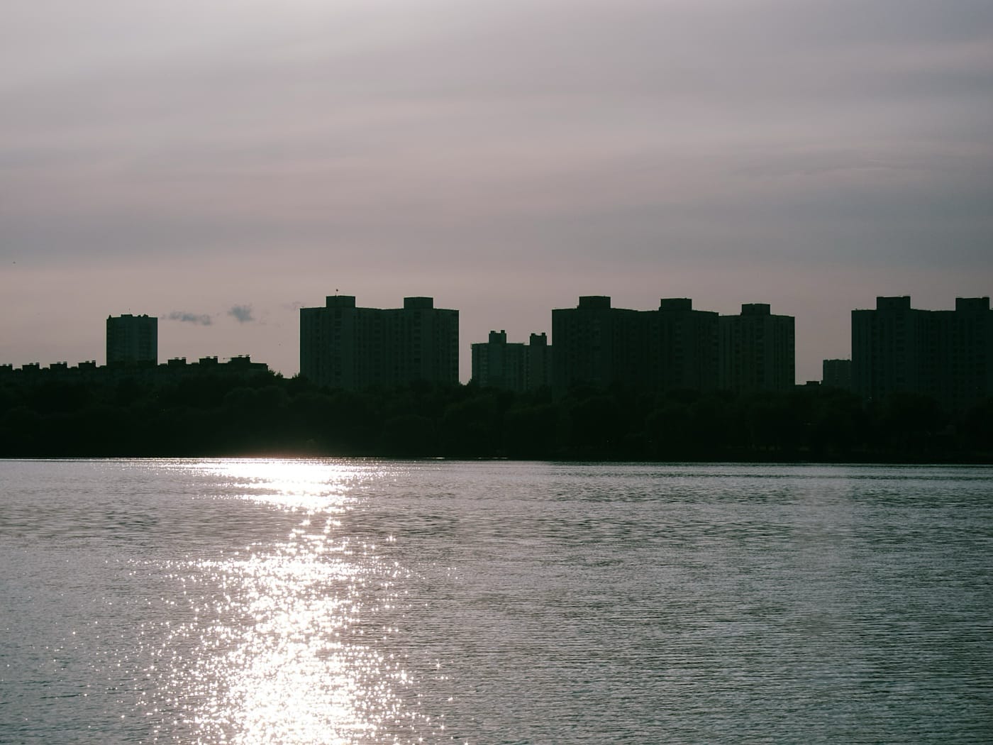 Тёмные силуэты домов на закате на берегу Чижовского водохранилища в Минске