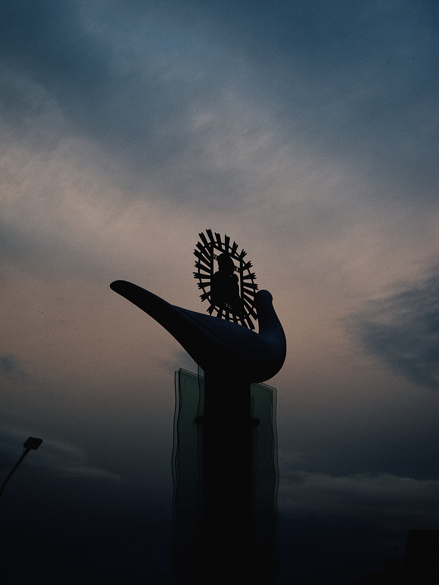 Силуэт скульптуры птицы на фоне вечернего неба.