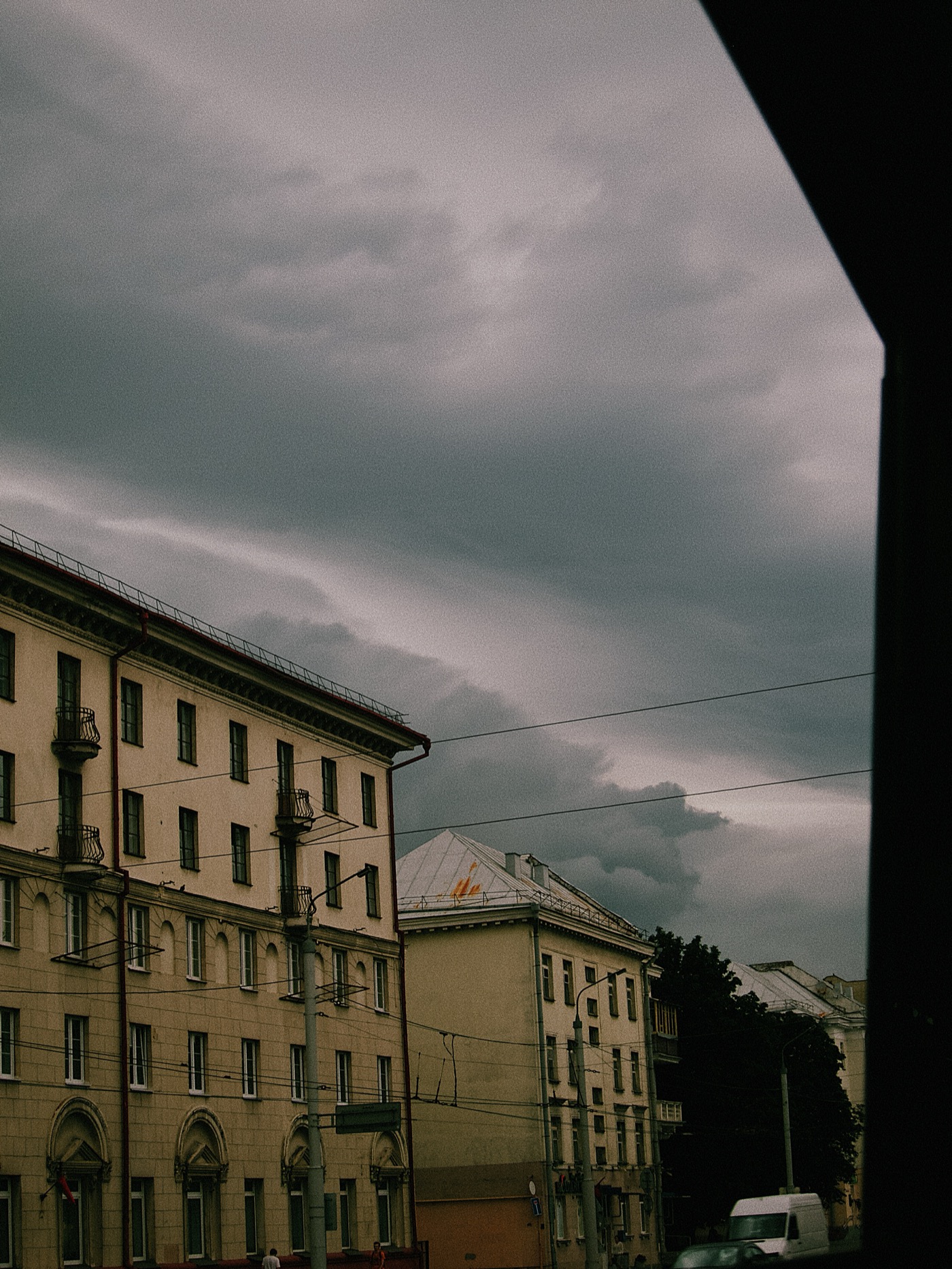 Темное небо с облаками над городскими зданиями, вид с окна.