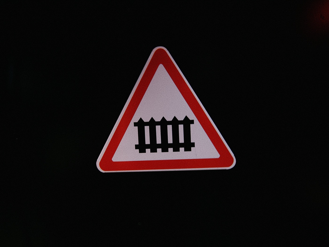 Знак предупреждения о железнодорожном переезде с изображением шлагбаума.