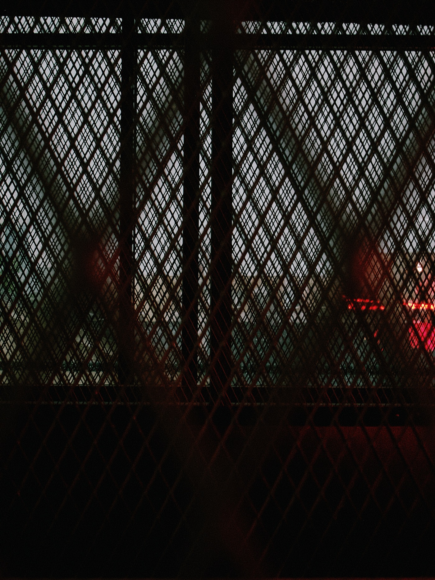 Сетка с ромбовидным узором на фоне вечернего неба и огней города.