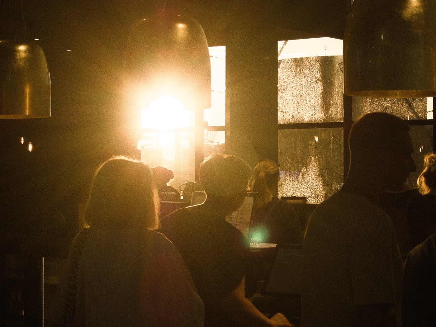 Силуэты людей на фоне яркого солнечного света, проникающего через окна.