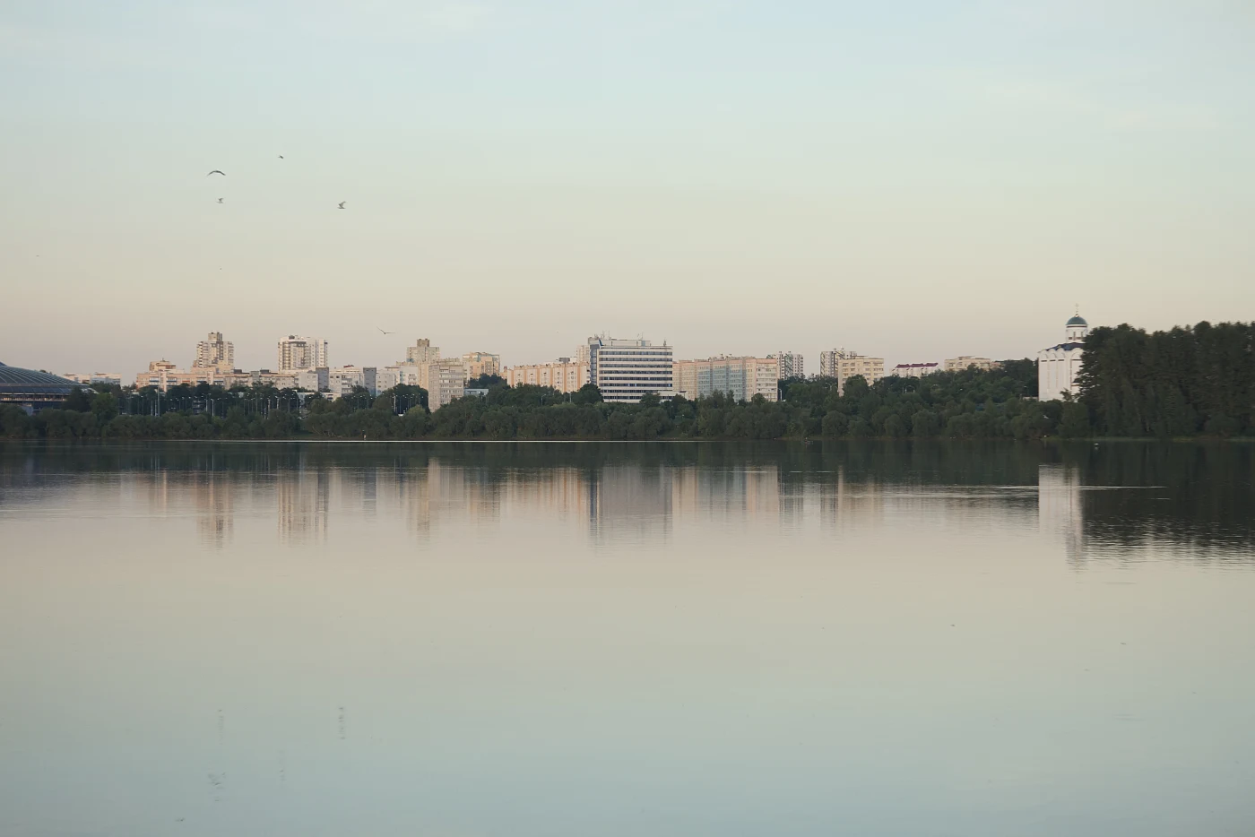 Cityscape against calm water reflecting buildings and sky.