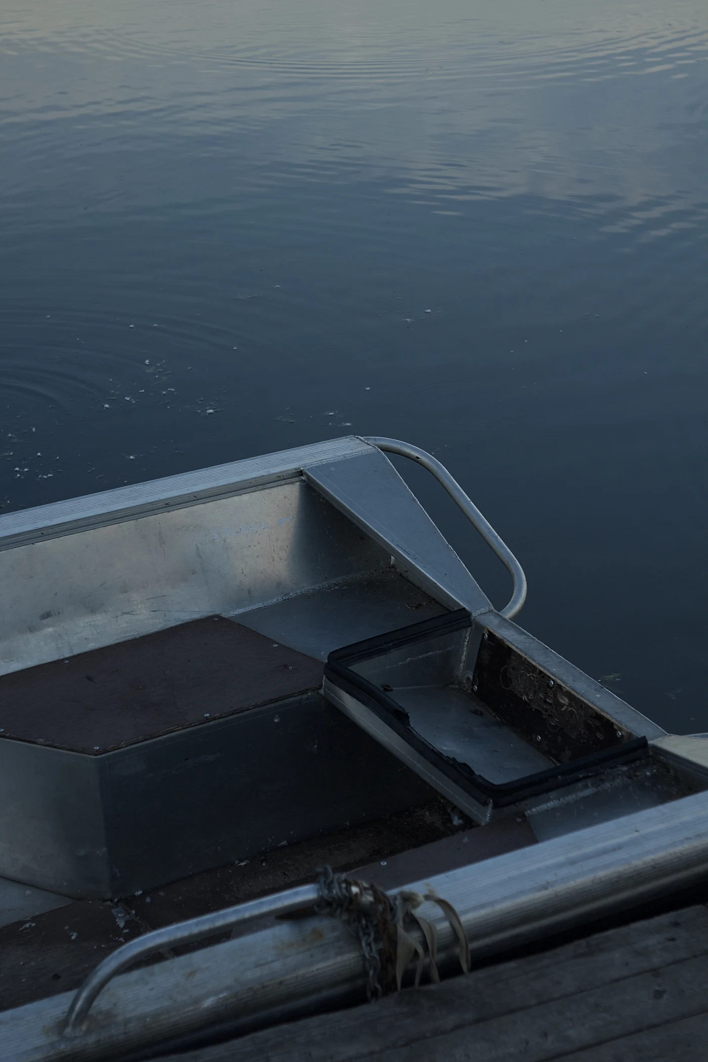 Part of a metal boat against calm water.