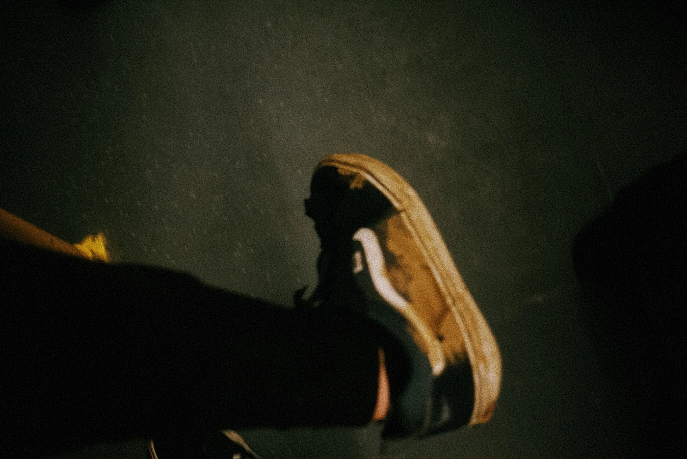 Старая обувь на ноге, фон темный, освещение мягкое.