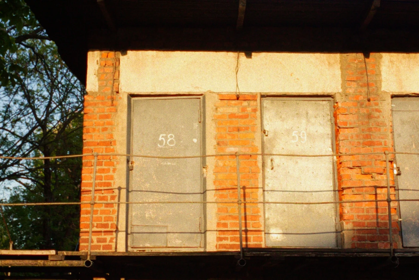 Two metal doors on a brick wall, numbered 58 and 59. Sunlight illuminates the facade.