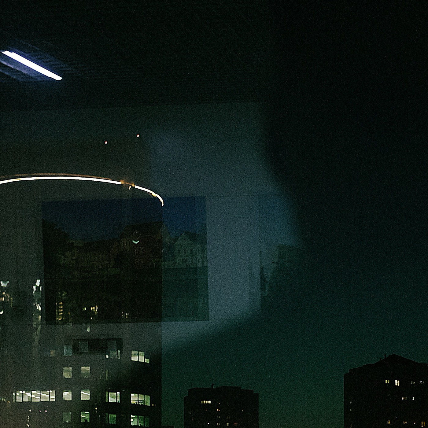 Ночной городской пейзаж с отражениями в окне и неоновым светом.