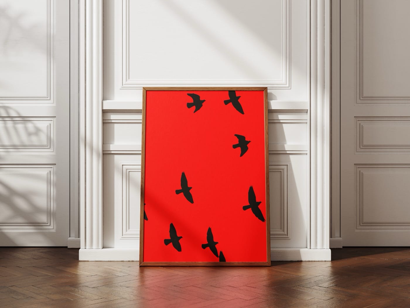 Красный плакат с чёрными птицами стоит на полу возле стены в красивом интерьере