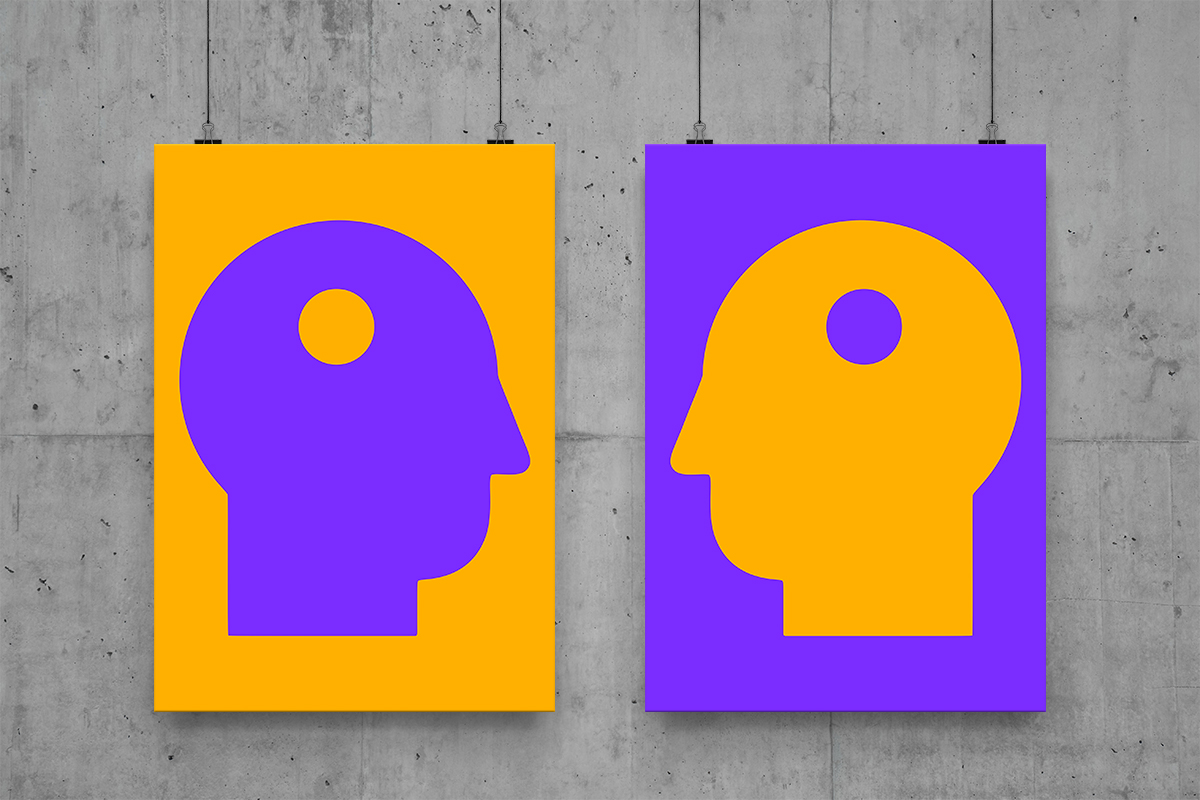 Two posters with head silhouettes, one orange and one purple, hanging on a concrete wall.